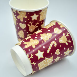 Christmas-themed paper cup featuring a rich burgundy background adorned with a playful gingerbread pattern. The design includes gingerbread men, candy canes, and holiday accents, creating a festive and cozy feel ideal for holiday celebrations.