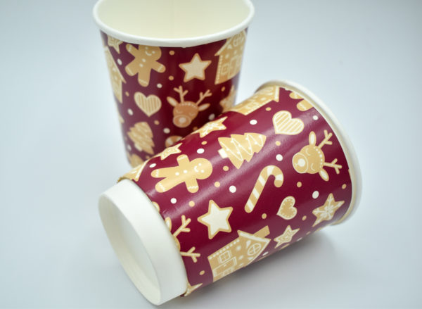 Christmas-themed paper cup featuring a rich burgundy background adorned with a playful gingerbread pattern. The design includes gingerbread men, candy canes, and holiday accents, creating a festive and cozy feel ideal for holiday celebrations.