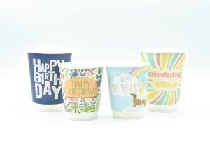 four paper cups happy birthday design from left to right grunge navy blue happy birthday, jungle theme happy birthday, sausage dog in the clouds happy birthday and groovy happy birthday cup deisgn